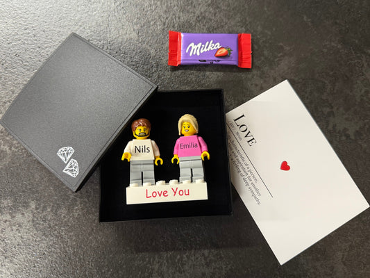 Zwei Personalisierte LEGO® Minifiguren auf einem individuellen Stein mit einer Geschenkbox und Grußkarte